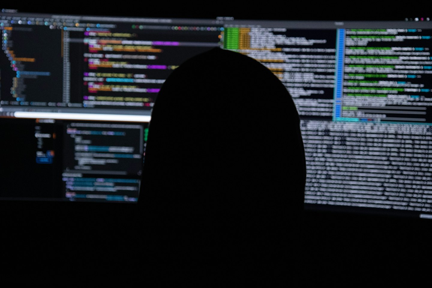 Silhouette of person looking at glowing computer code.